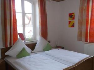 łóżko z białą pościelą i zielonymi poduszkami w pokoju w obiekcie Gasthaus zum Schwanen w mieście Oberkirch