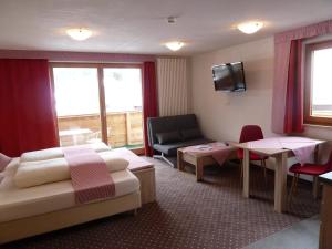 a hotel room with two beds and a couch and a table at Alpina Appartements in Haldensee