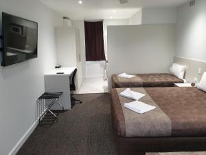 a hotel room with two beds and a flat screen tv at Naracoorte Hotel Motel in Naracoorte