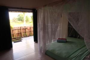 ein Schlafzimmer mit einem grünen Bett und einem Fenster in der Unterkunft THE NYAMO surf & stay in Pulukan