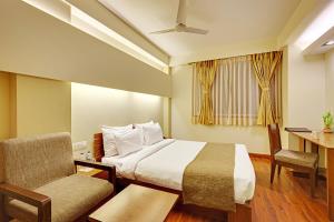 a hotel room with a bed and a desk and a chair at Whispering Palms Hotel Jaipur in Jaipur