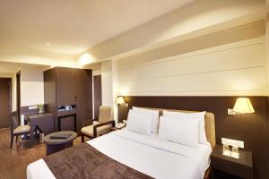 a hotel room with a bed and a desk at Whispering Palms Hotel Jaipur in Jaipur