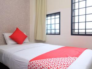 a bed with a red pillow and two windows at Hotel De' Tees, Masai Utama in Pasir Gudang