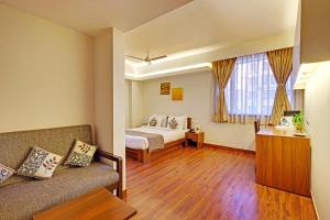 a hotel room with a bed and a couch at Whispering Palms Hotel Jaipur in Jaipur