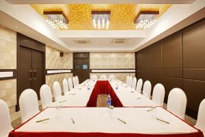 a long table in a room with white chairs at Whispering Palms Hotel Jaipur in Jaipur