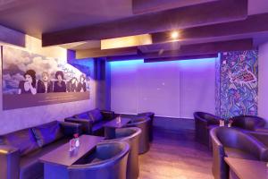 a restaurant with purple chairs and tables and a large screen at Whispering Palms Hotel Jaipur in Jaipur