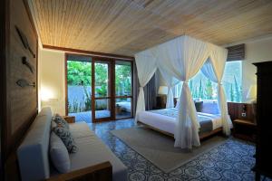 1 dormitorio con 1 cama con dosel en Jeeva Santai Villas, en Senggigi 