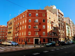 un edificio rosso su una strada cittadina con auto parcheggiate di My Penthouse Valencia a Valencia