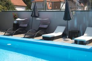 eine Gruppe von Stühlen und Sonnenschirmen neben einem Pool in der Unterkunft Hotel Restaurant Römerhof in Leibnitz
