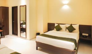 een slaapkamer met een groot bed met groene kussens bij Treebo Trend Balaji Residency in Kolhapur