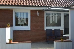 ein Backsteinhaus mit zwei Stühlen und einem Fenster in der Unterkunft Ferienhaus Stana in Leer