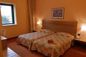 フォッサーノにあるHotel Romanisioのベッド2台と窓が備わるホテルルームです。