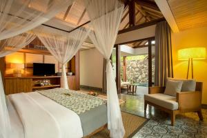 a bedroom with a bed and a chair and a television at Jeeva Santai Villas in Senggigi 