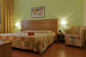 a hotel room with a bed and a chair at Hotel Romanisio in Fossano