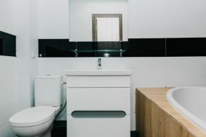 a white bathroom with a toilet and a sink at Luxury Apartment in Sumy