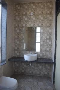 a bathroom with a sink and a toilet and a mirror at Oasis Resort in Diveagar