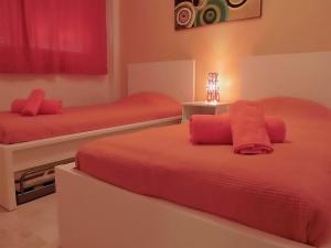 マニルバにあるBalcones de La Duquesaのベッドルーム1室(赤いシーツとランプ付きのベッド2台付)