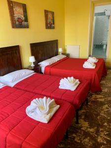 two beds in a hotel room with red sheets at Amico Hotel in Rome