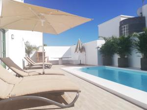 a swimming pool with two lounge chairs and an umbrella at Villa Elena in Puerto del Carmen