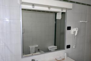 a bathroom with a toilet, sink and mirror at Hotel Romanisio in Fossano