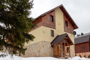 a large wooden building with snow on the ground at Apartments In in Jahorina