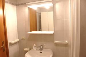 bagno bianco con lavandino e specchio di Appartamento di Viola & Elia a Predazzo