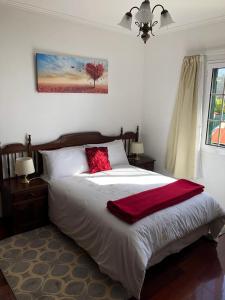 een slaapkamer met een bed met een rode deken erop bij Apartment with beautiful ocean and city view in Funchal