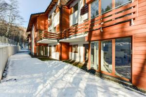 什切爾克的住宿－Apartament Wróbelkowo，木结构建筑旁的雪覆盖人行道