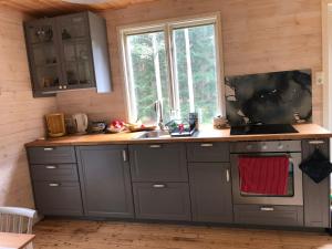 a kitchen with gray cabinets and a sink and a window at Ferienhaus Småland in Fågelfors