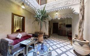 een woonkamer met een bank en een palmboom bij Riad abaka by ghali 2 in Marrakesh