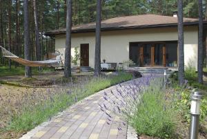 uma casa com uma rede em frente em Jūrmalas Priedes em Apsuciems