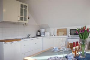 キュールングスボルンにあるFewo-Perner Meerblickの白いキャビネットと花のテーブル付きのキッチンが備わります。
