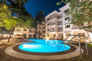 a swimming pool in front of a building at night at Resort Paloma De Goa in Colva