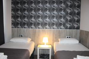 2 camas individuales en una habitación con una pared con tazones en BCN Condal Hostal, en Barcelona