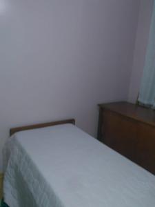 - une chambre avec un lit blanc et une commode en bois dans l'établissement Apartamento Centro Gramado, à Gramado