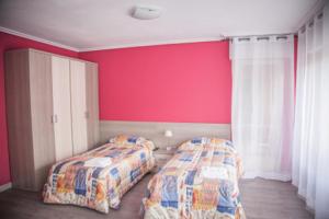 a bedroom with two beds and a red wall at Pensión Parque del Ebro in Logroño