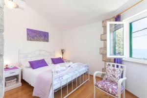 1 dormitorio blanco con 1 cama y 1 silla en Holiday home Lavanda Grubisic Tucepi en Tučepi