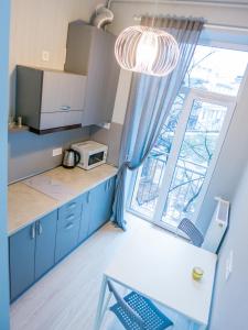 リヴィウにあるSnizhna 4の青いキャビネットと窓付きの小さなキッチン