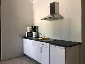a kitchen with white cabinets and a black counter top at FANTÁSTICO APTO. 6 pax, TABLERO 5, cerca PLAYA INGLÉS in El Tablero