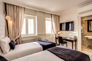 a hotel room with two beds and a desk at Hotel Domus Mea in Rome