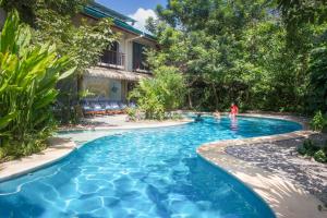 uma piscina em frente a uma casa com duas pessoas em Olas Verdes Hotel em Nosara