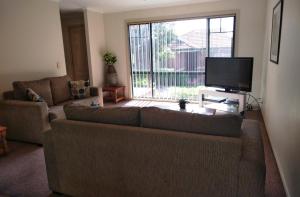a living room with a couch and a large window at Mount Waverley Townhouses in Mount Waverley