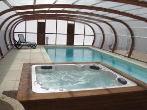 a large swimming pool with a hot tub in a building at Les Chènevottes au Hameau 1936 in Cherveux