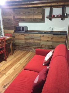 a red couch in a living room with a kitchen at La Tzambretta in Aosta