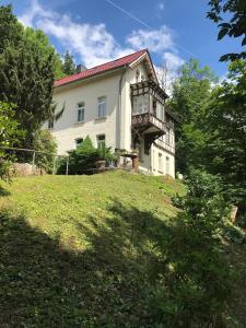 uma grande casa branca numa colina com árvores em Schöne Ferienwohnung em Eisenach