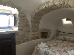 sypialnia z łóżkiem i kamienną ścianą w obiekcie A Due Passi dal Centro - Trullo w Alberobello
