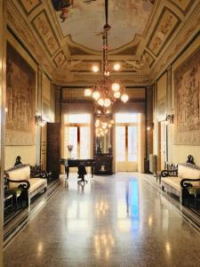 ジョヴィナッツォにあるPalazzo Framarino dei Malatestaのピアノとシャンデリアが備わる広い客室です。