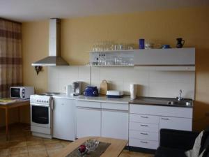 een keuken met witte kasten en een fornuis met oven bij Pension Nama in Spiegelau