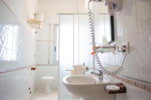 a white bathroom with a sink and a mirror at Hotel Il Girasole in Bova Marina +99 photos
