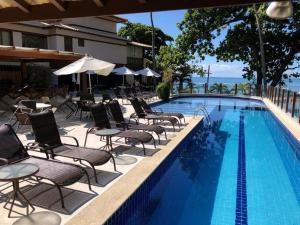 een zwembad met stoelen en parasols voor een hotel bij Apartamento Porto Praia do Forte in Praia do Forte